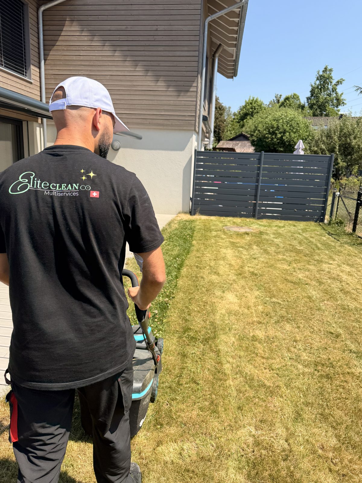 Technicien EliteCleanCo Multiservices tondant une pelouse à Lausanne, canton de Vaud
